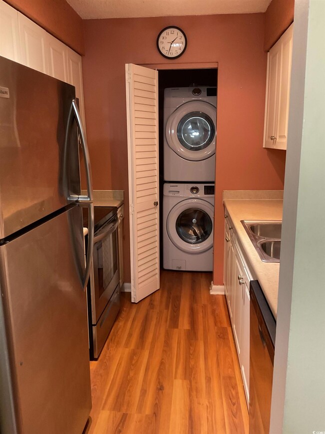 Kitchen featuring white cabinetry, stacked washing