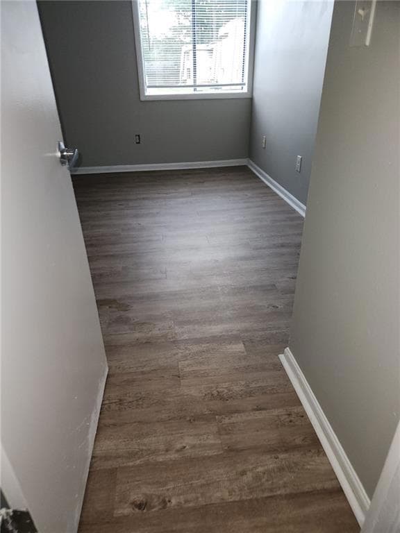 Unfurnished room with baseboards and dark wood-sty