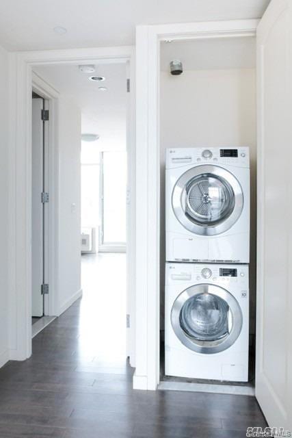 Laundry area with stacked washer / drying machine and dark wood-style floors