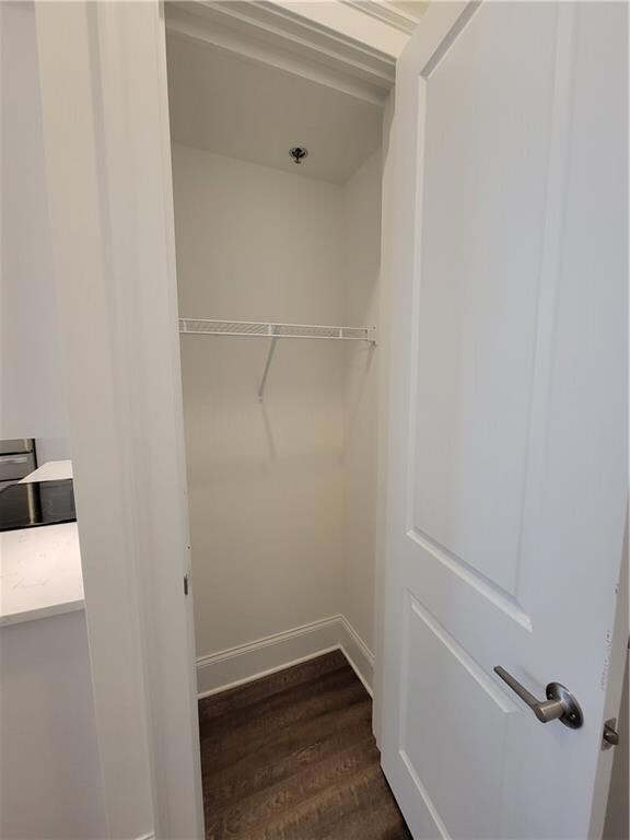 Entryway coat closet featuring dark wood-type floo