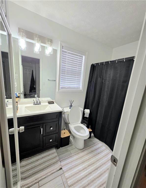 Bathroom featuring curtained shower, vanity, a textured ceiling, and wood finish floors