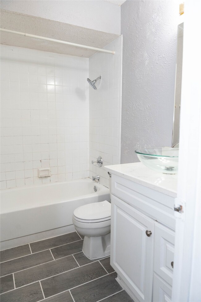 Full bath with a textured wall, shower / washtub combination, vanity, and wood tiled floors