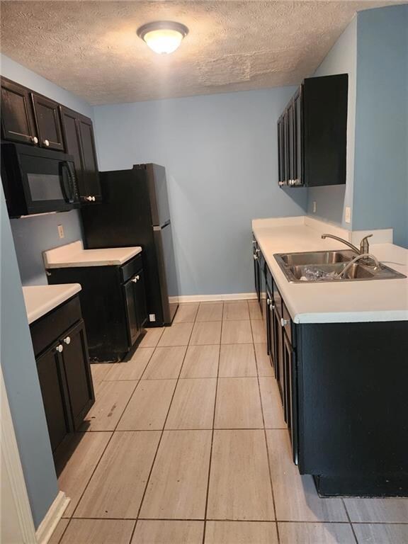 Kitchen with black microwave, fridge, light counte