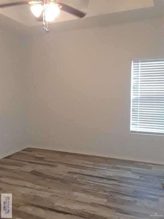 Spare room with baseboards, wood finished floors, and a ceiling fan