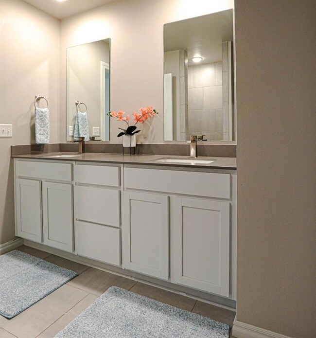 Full bathroom featuring double vanity, tile patterned floors, and baseboards