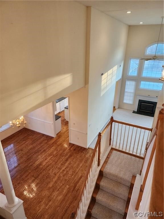 Stairs featuring high vaulted ceiling, ornate columns, dark hardwood / wood-style floors, and a notable chandelier