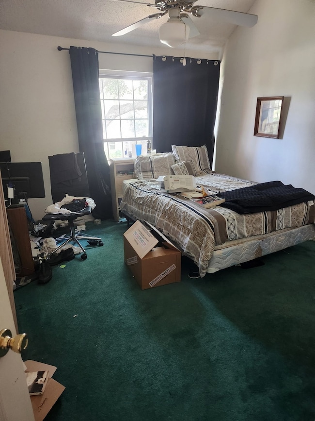Carpeted bedroom featuring ceiling fan and a textured ceiling