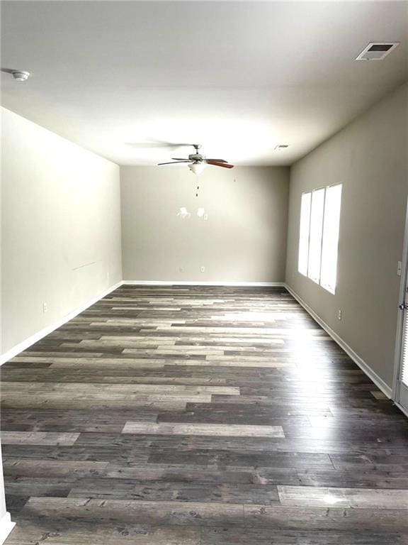Empty room with a ceiling fan, dark wood finished floors, and a smoke detector