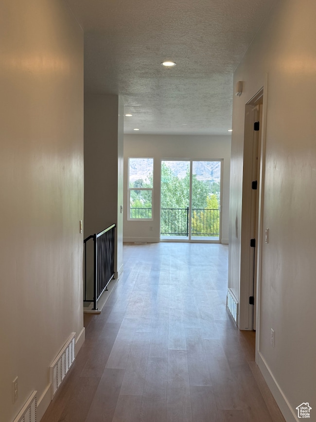 Corridor with a textured ceiling and light wood-style flooring