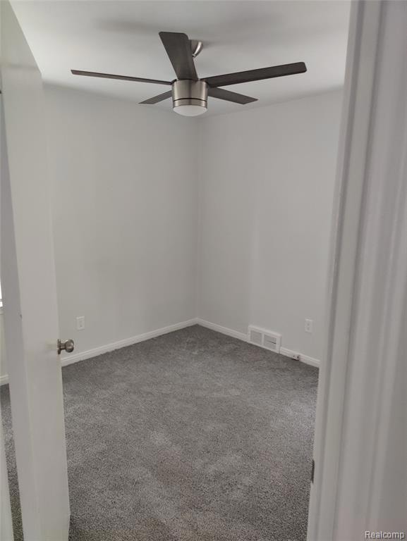 Carpeted spare room with a ceiling fan and baseboards