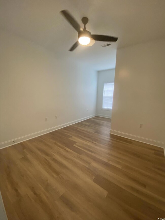 Unfurnished room with wood finished floors and a ceiling fan