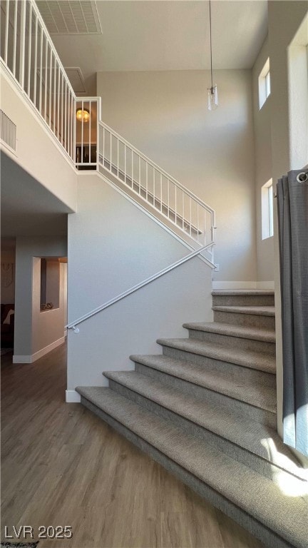 Staircase featuring a high ceiling, wood finished