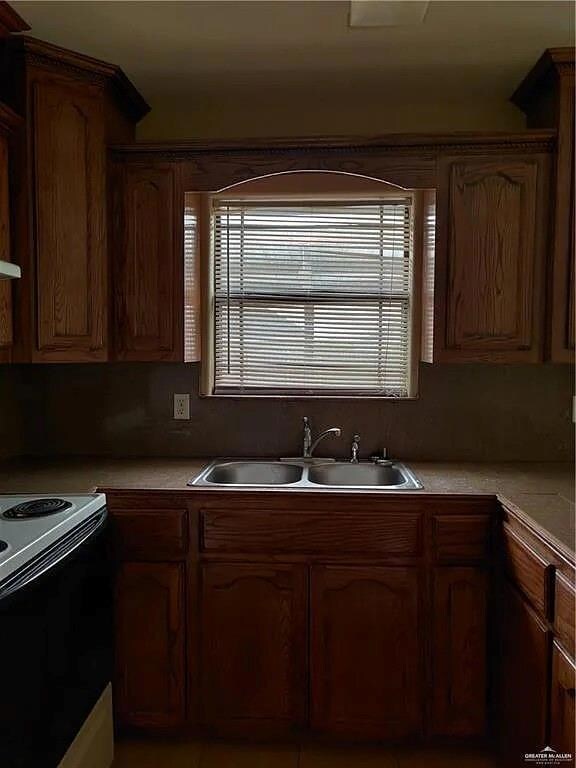 Kitchen with black electric range, light countertops, and a sink