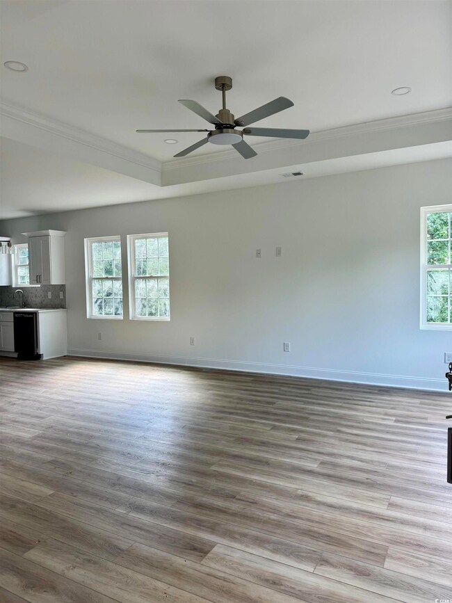 Unfurnished living room featuring crown molding, wood finished floors, a ceiling fan, and recessed lighting