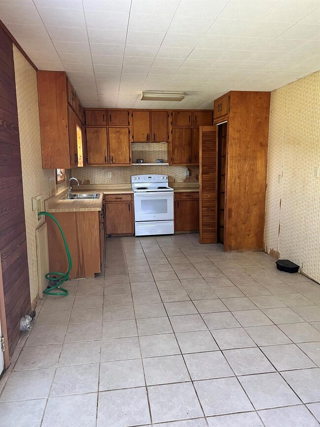 Kitchen with electric range, a sink, brown cabine