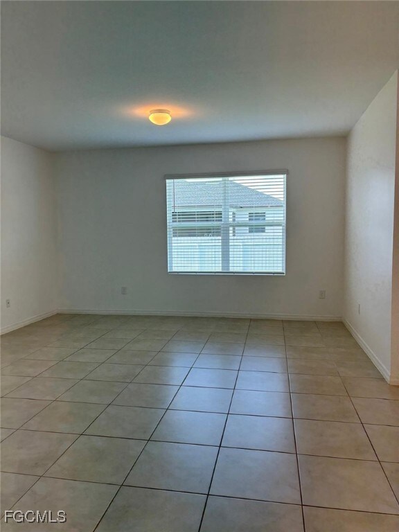 Spare room with light tile patterned flooring and baseboards