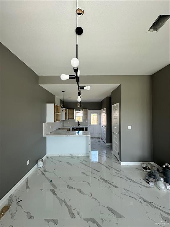 Kitchen featuring kitchen peninsula, a notable chandelier, sink, light tile floors, and pendant lighting
