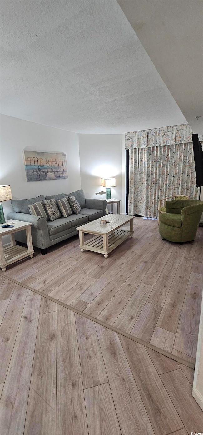 Living area featuring light wood-style floors and a textured ceiling