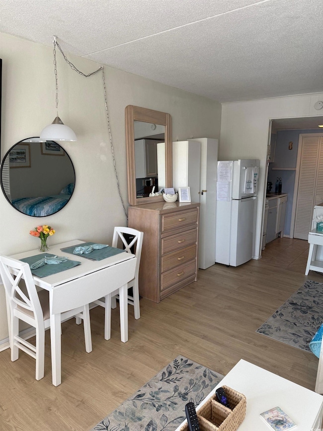 Kitchen with freestanding refrigerator, light wood-style flooring, and a textured ceiling