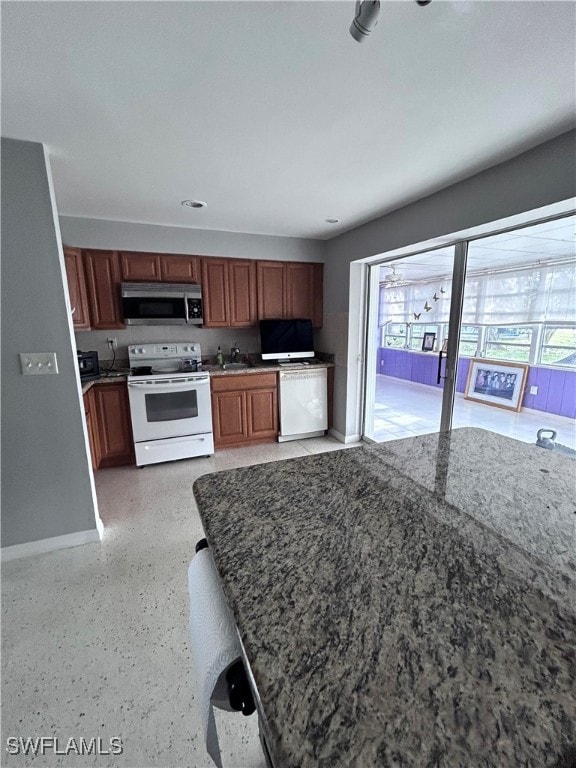 Kitchen featuring white appliances, dark stone cou