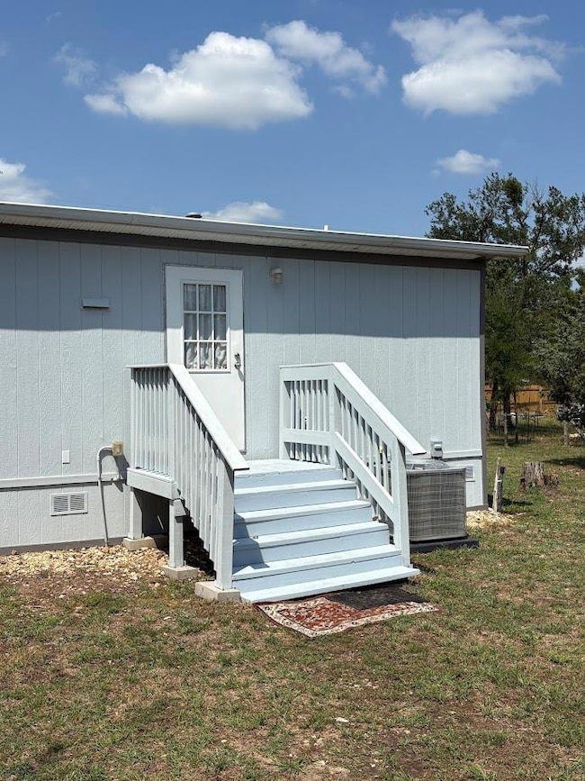 Back of property featuring a lawn and central AC 
