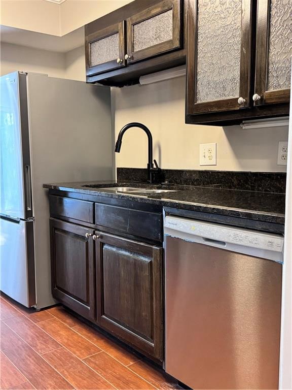 Kitchen with dishwasher, stainless steel refrigerator, and dark brown cabinets