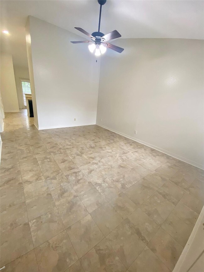 Empty room with ceiling fan, vaulted ceiling, and