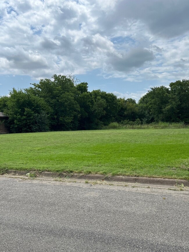 View of asphalt road with curbs, a rural view, and a wooded view