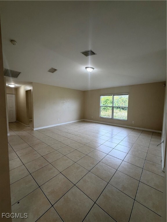 Empty room featuring light tile patterned flooring and baseboards