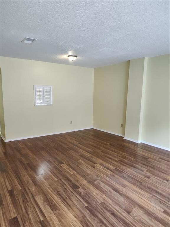 Unfurnished room with a textured ceiling and dark wood finished floors