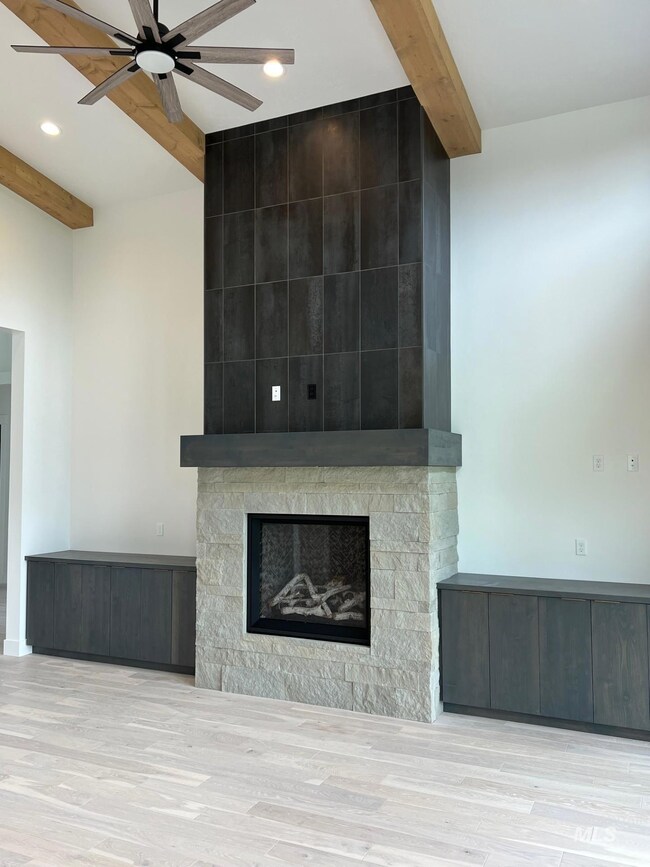 Unfurnished living room with beam ceiling, wood finished floors, a ceiling fan, a fireplace, and recessed lighting