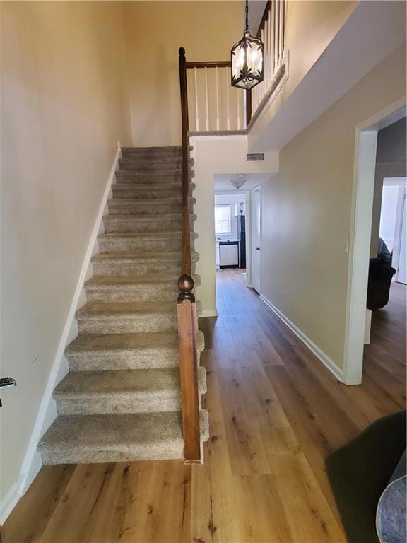 Stairs with wood finished floors and a high ceiling