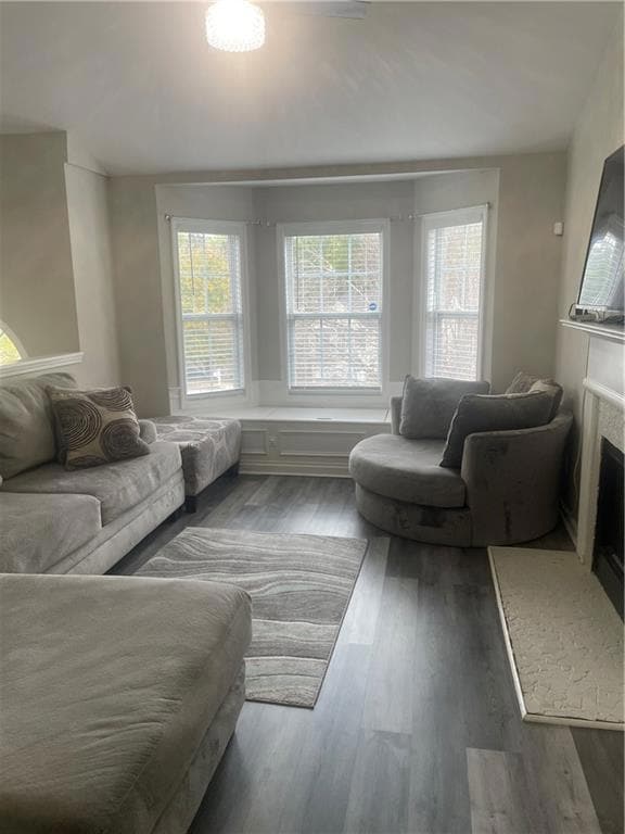 Living area with plenty of natural light, wood finished floors, and a fireplace with raised hearth