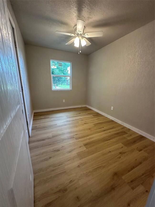 Empty room with ceiling fan, hardwood / wood-style