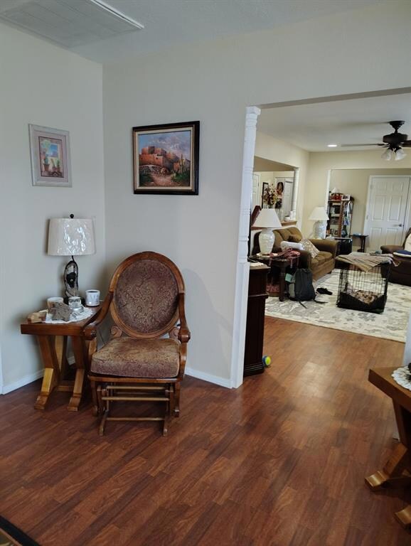 Living area featuring ceiling fan and dark hardwoo