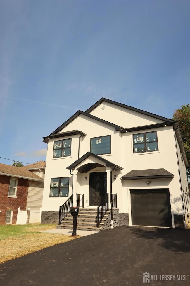 View of front facade featuring stucco siding, asphalt driveway, and an attached garage