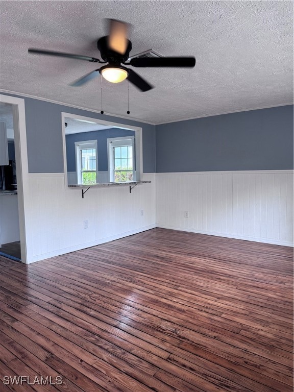 Unfurnished room featuring a wainscoted wall, dark