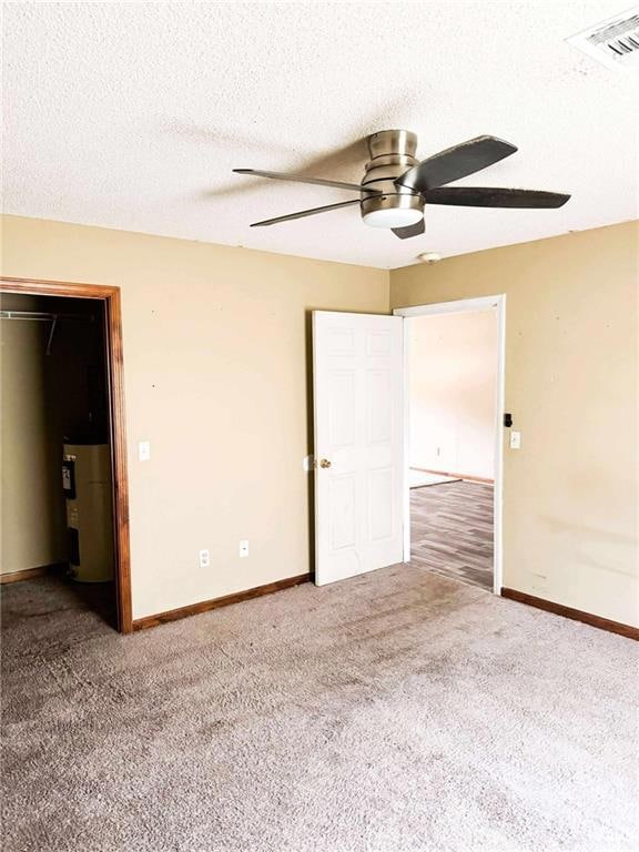 Unfurnished bedroom with water heater, carpet floors, baseboards, a textured ceiling, and ceiling fan