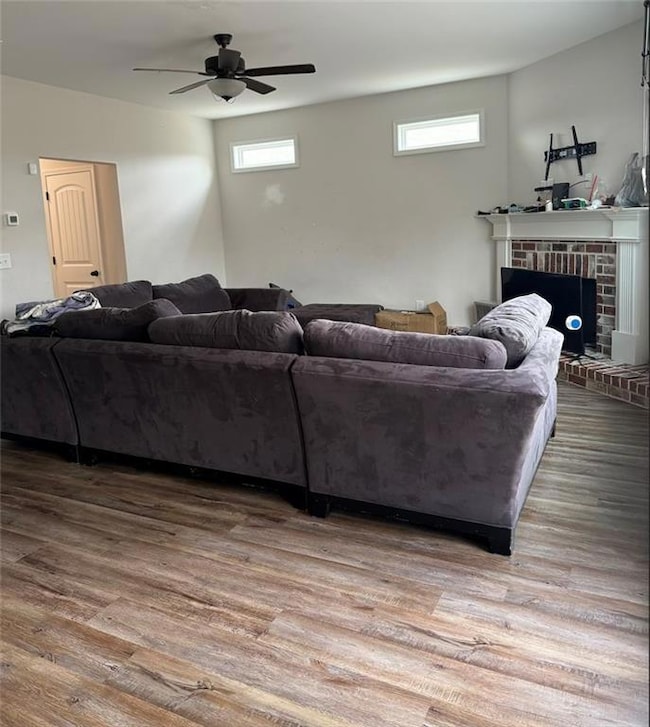 Living area with ceiling fan, plenty of natural light, and wood finished floors