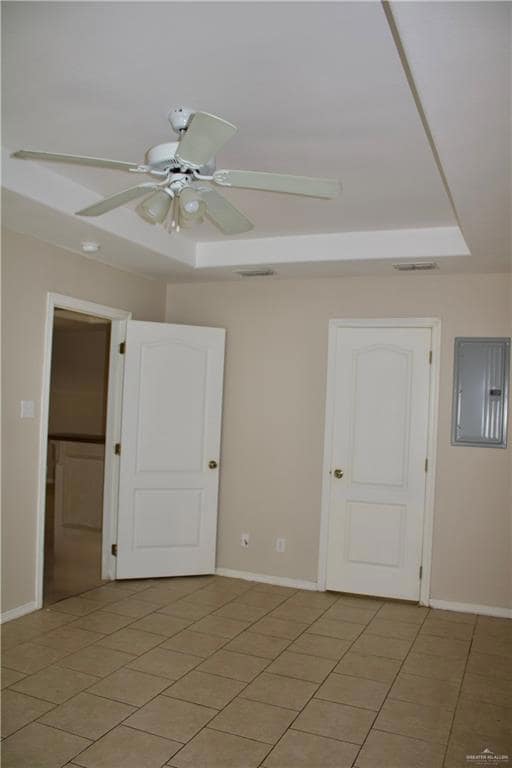 Spare room featuring ceiling fan, electric panel, light tile patterned floors, and a raised ceiling