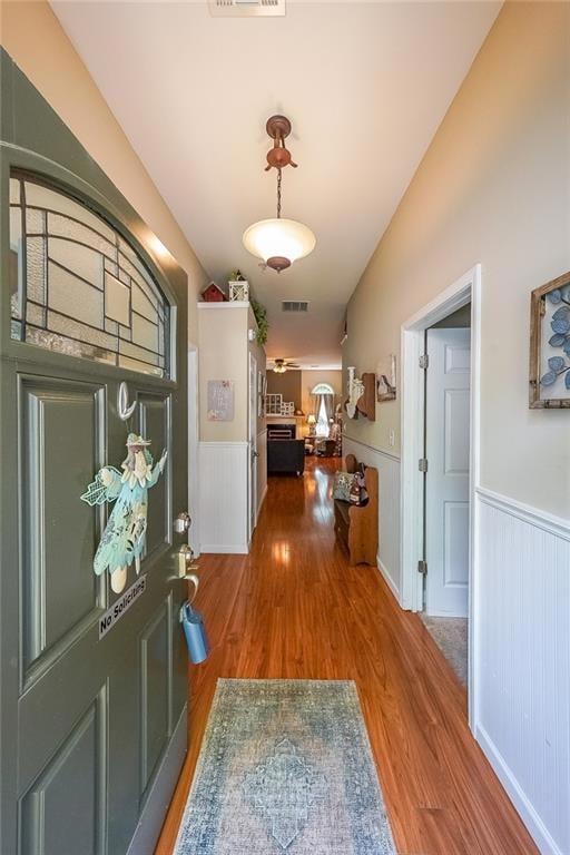 Hallway featuring wood finished floors and wainsco