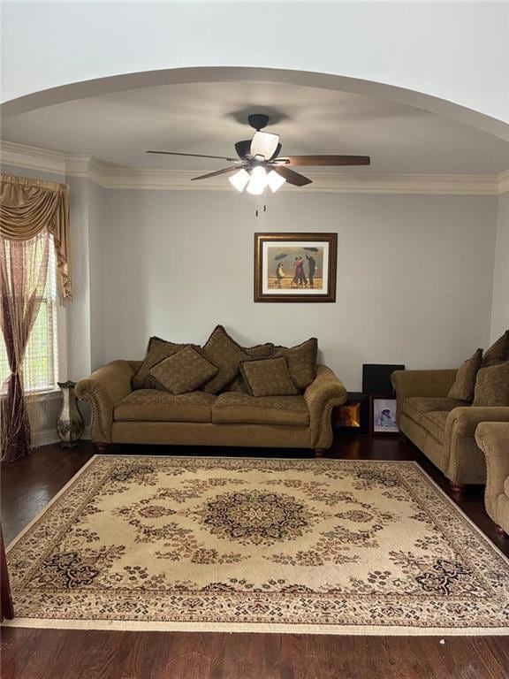 Living room featuring arched walkways, ornamental molding, ceiling fan, and wood finished floors