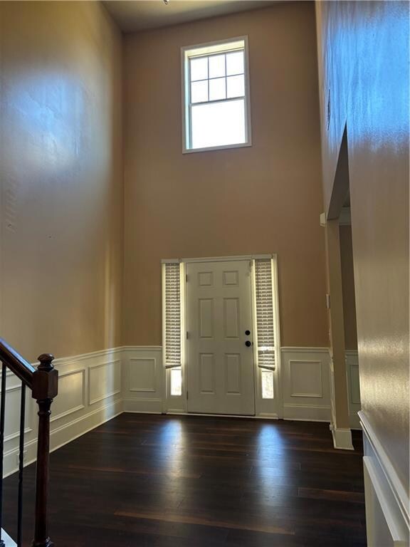 Entrance foyer featuring stairs, a towering ceiling, and dark wood finished floors