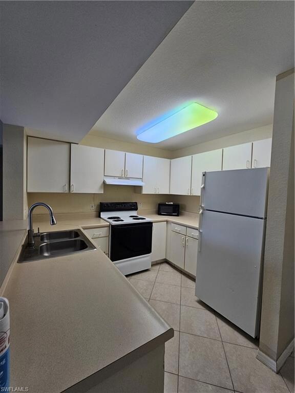 Unfurnished living room featuring baseboards, visible vents, a sink, and light tile patterned flooring