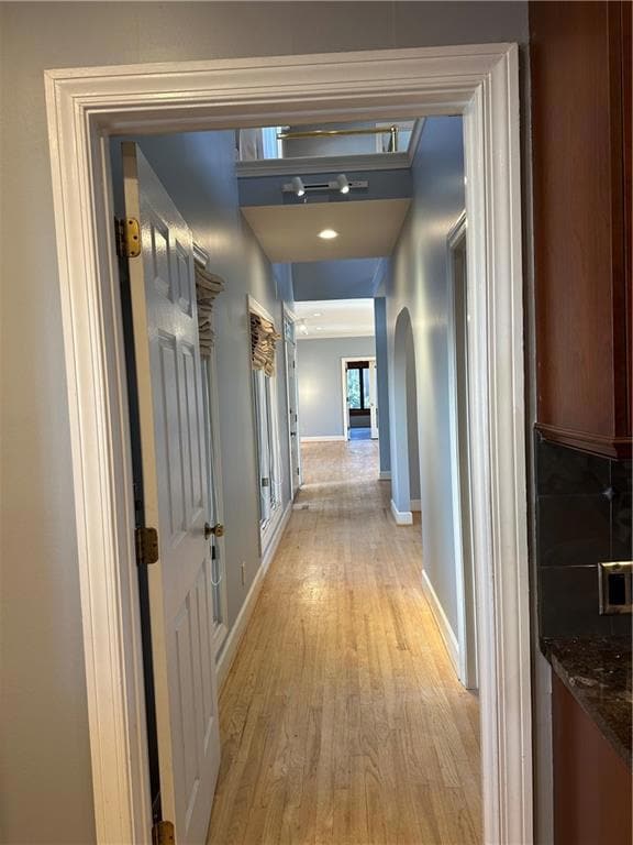 Hallway featuring baseboards, arched walkways, and