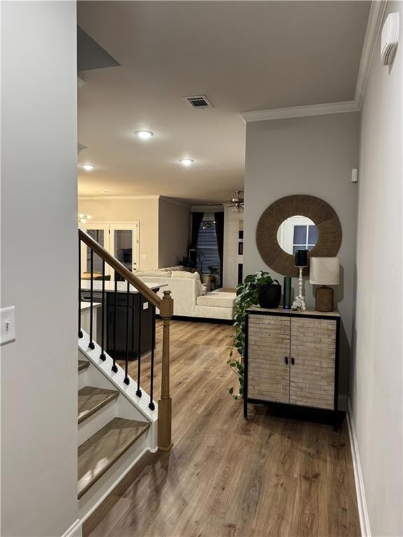Stairway with wood-type flooring and crown molding