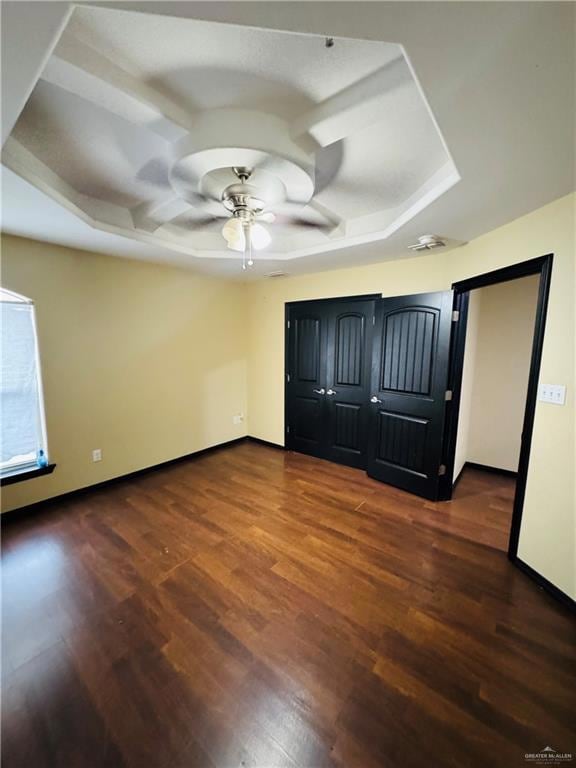 Unfurnished bedroom featuring dark wood-style floors, ceiling fan, coffered ceiling, and baseboards