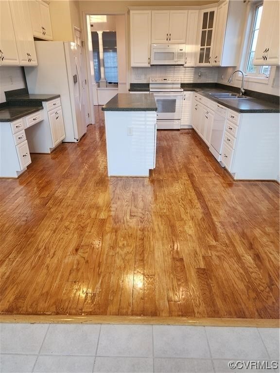 Kitchen with a center island, sink, white cabinets, white appliances, and light hardwood / wood-style flooring