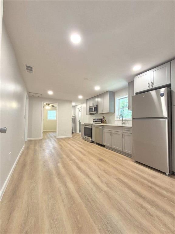 Kitchen with appliances with stainless steel finishes, light wood-style flooring, recessed lighting, light countertops, and gray cabinets