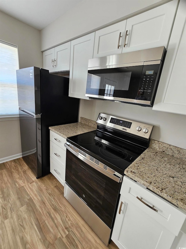 Kitchen featuring white cabinets, light wood-style